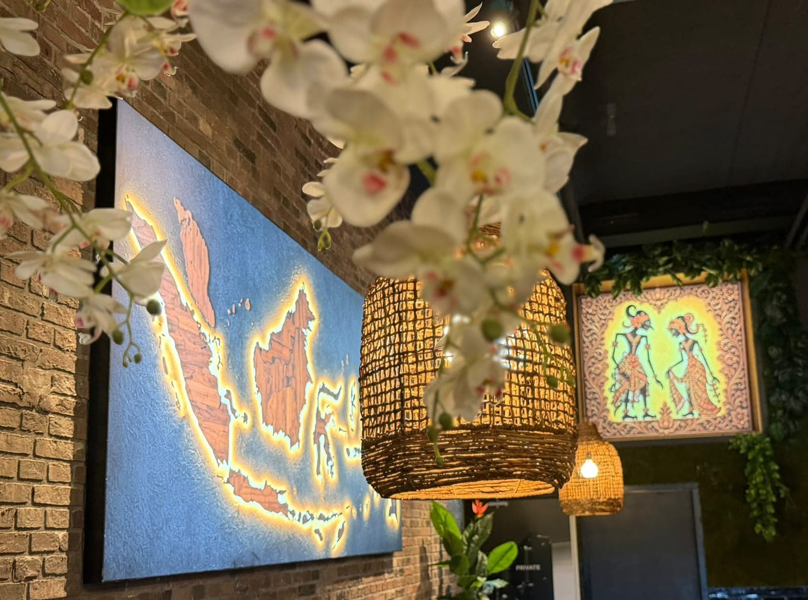 Interieur van Bersama met een lichtgevende kaart van Indonesië, rotan hanglampen en orchideeën